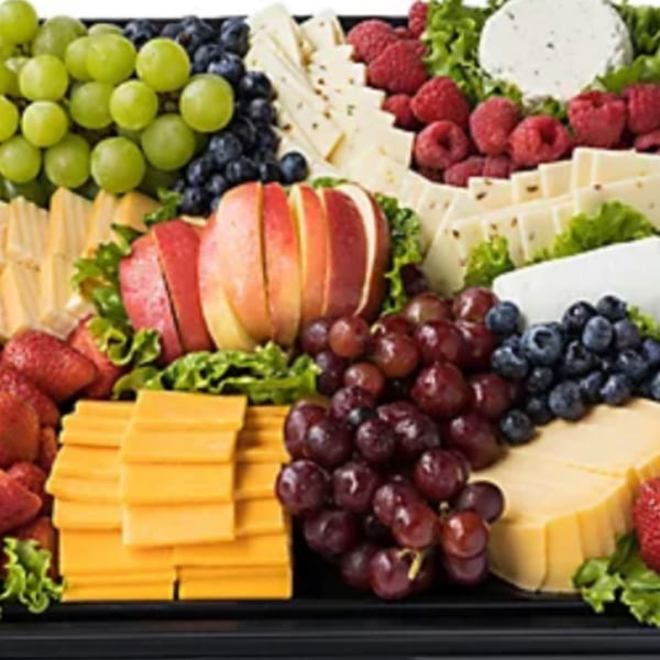 A large platter filled with various cheeses, green and red grapes, blueberries, raspberries, strawberries, and sliced apples.